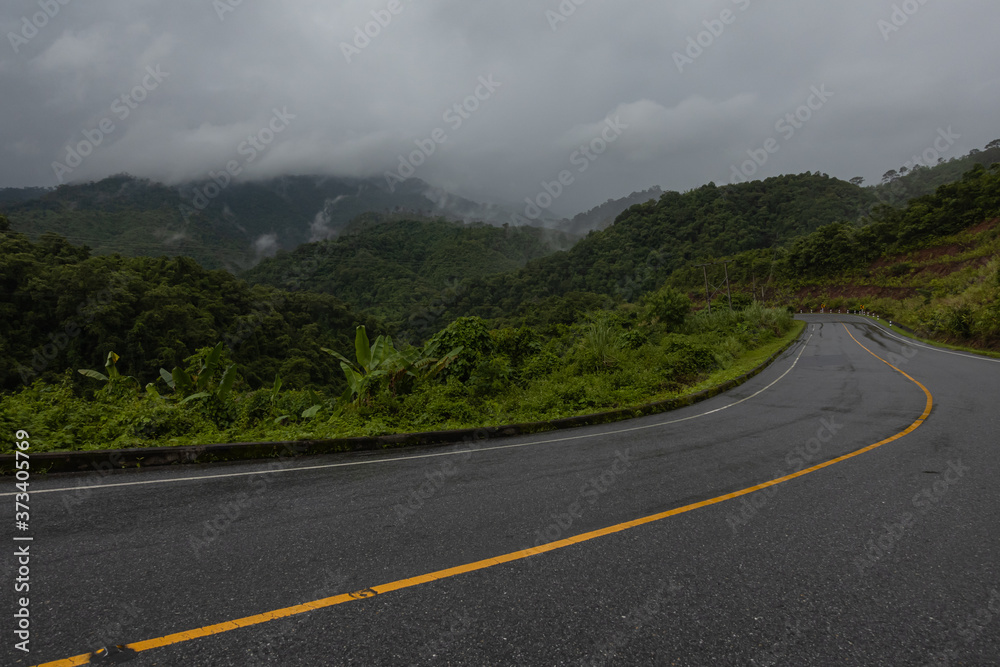 Logistic concept aerial view of countryside road - motorway passing through the serene lush greenery and foliage tropical rain forest mountain landscape