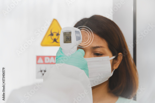 Middle-aged women receive a digital temperature probe Infravermelho body infrared frontal thermometer to measure fever during hospitalization (normal temperature 34 degrees Celsius)
 photo