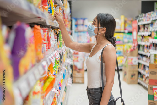 Asian woman wearing face mask shopping in suppermarket. safety and coronavirus pandemic concept. New normal lifestyle. photo