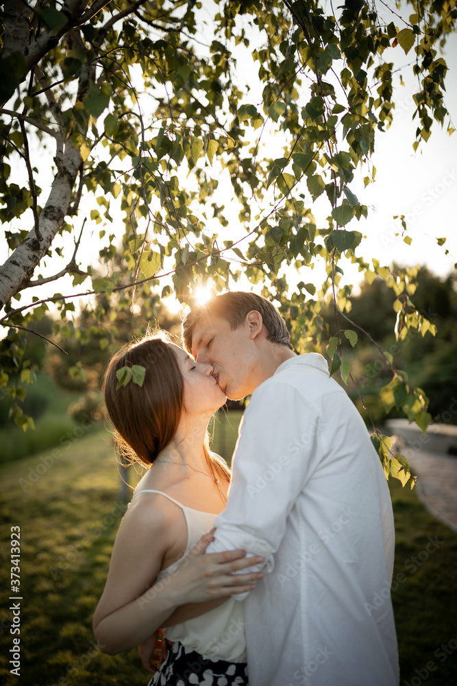 happy young couple is kissing on nature and sunset
