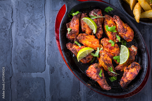 Roasted chicken wings in barbecue sauce with lime and baked potatoes