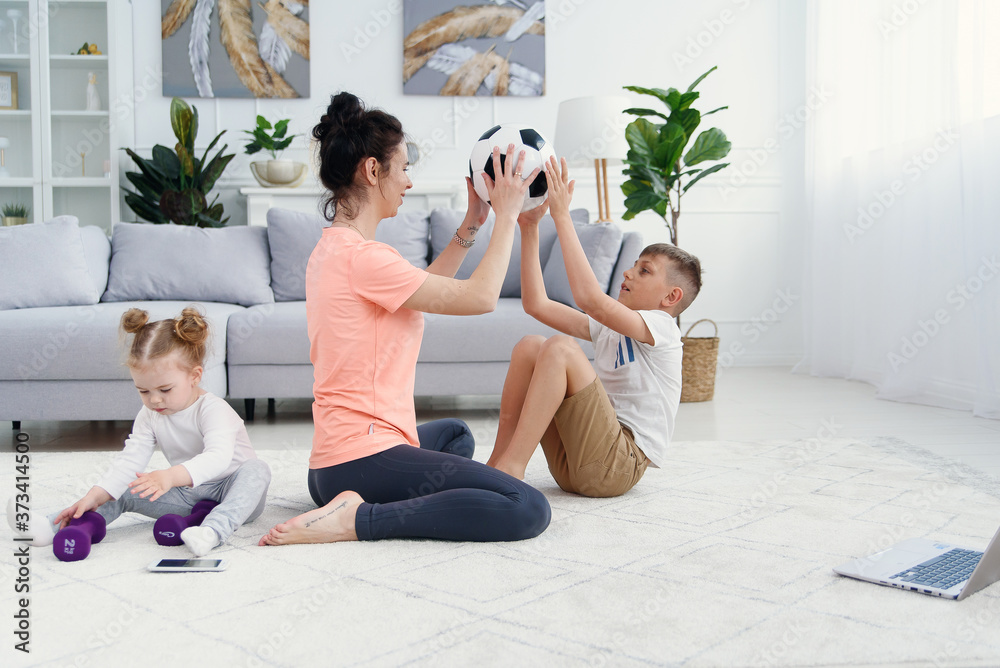 Athletic mom with son doing morning workout at home. Mom and son doing exercises for the stomach together. Athletic mom with son doing morning workout at home. Mom and son doing exercises for the stomach together.
