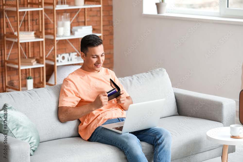 Man with laptop booking tickets online at home