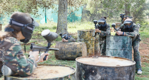 Two active opposing teams playing paintball against each other outdoors in forest.