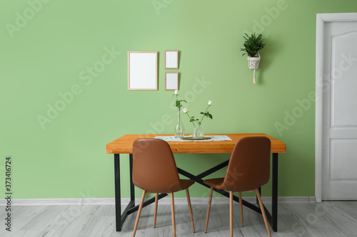 Table and chairs near color wall © Pixel-Shot