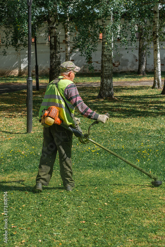 a man mows the grass on the lawn with a trimmer