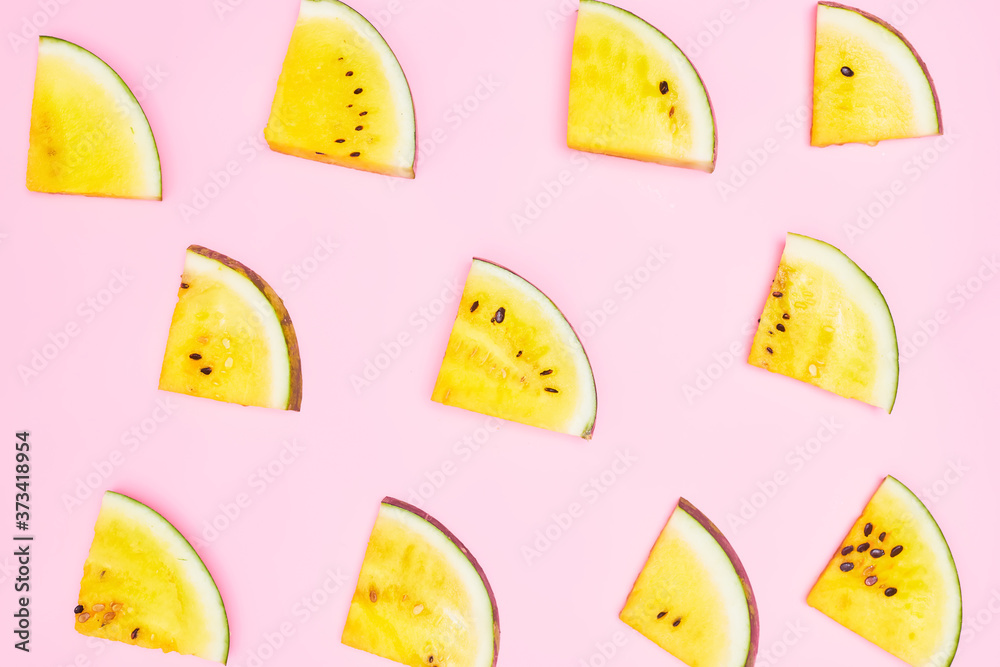 slices of yellow watermelon on a pastel pink background, copy space, layout