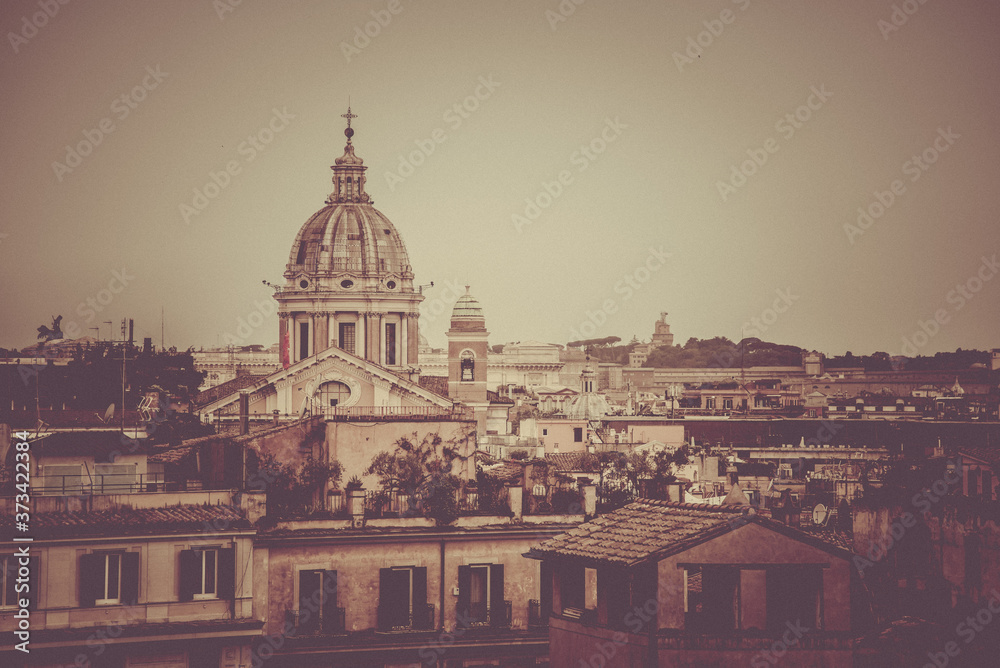 Rome skyline with old colorful houses and rooftop terraces on sunny day. Dome of San Carlo al Corso basilica on the background. Rome, Italy