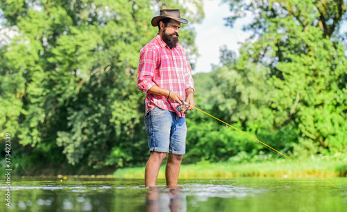 Some kind meditation. Fish normally caught in wild. Trout farm. Fisherman alone stand in river water. Man bearded fisherman. Fisherman fishing equipment. Hobby sport activity. Calm and peaceful mood