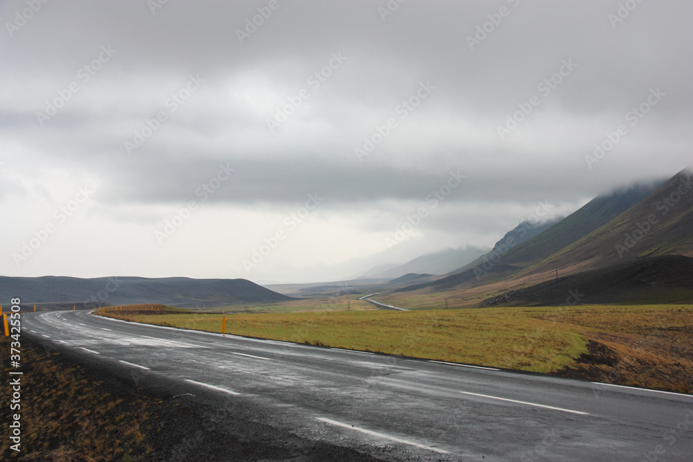 An empty winding road in the volcanic mountains of Iceland on a cloudy day