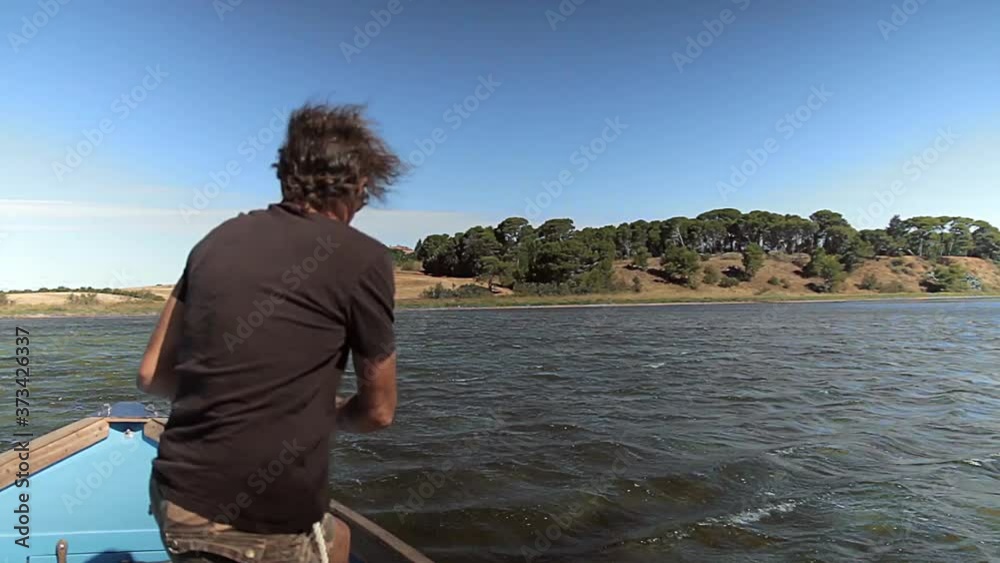 Un homme remonte l'encre de sa barque sur la lagune de Thau. Un homme remonte l'encre de sa barque sur la lagune de Thau.