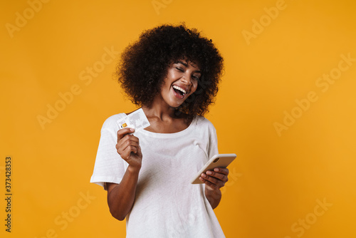 Image of african american girl holding credit card and mobile phone