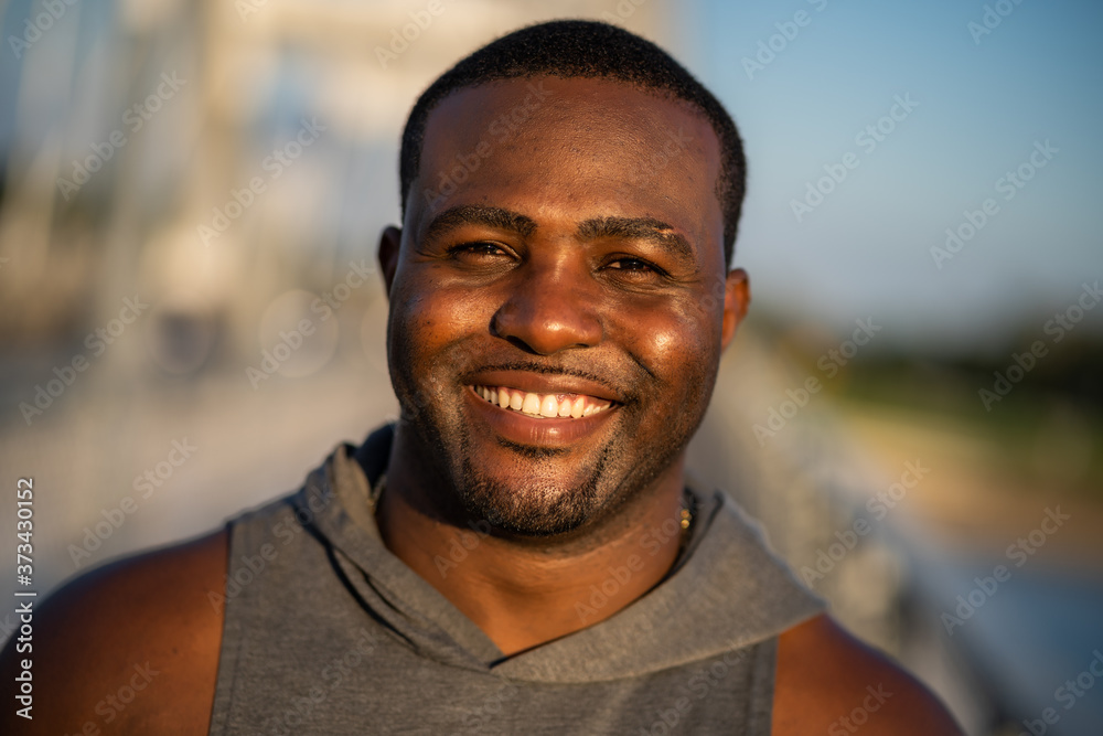 Portrait of young cheerful african-american man in sports clothing who is looking at camera and smiling. - obrazy, fototapety, plakaty 