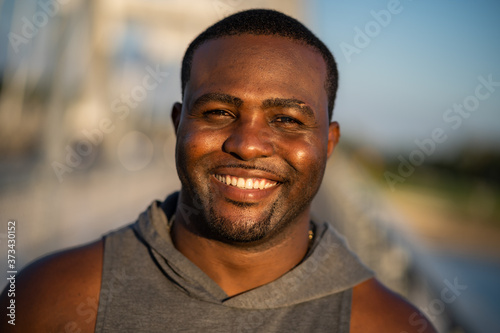 Portrait of young cheerful african-american man in sports clothing who is looking at camera and smiling.