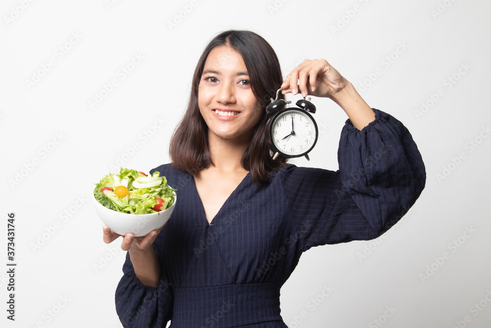 Young Asian woman with clock and salad. Young Asian woman with clock and salad.