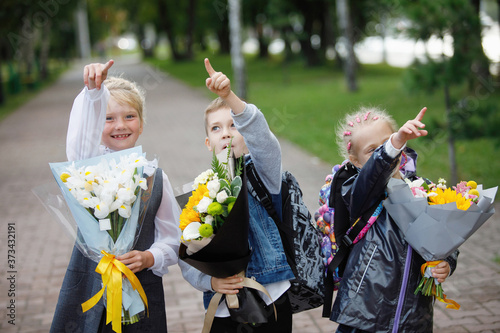 Schoolchildren, a boy and girls with bouquets of flowerss. photo