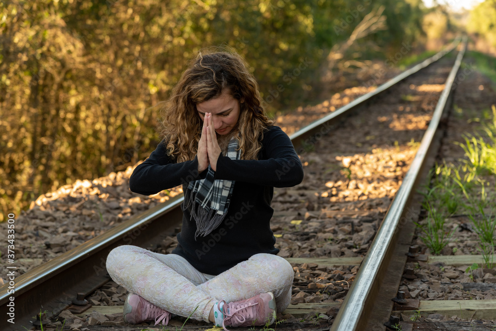 Blonde Brazilian woman meditating on the rails of a train line Blonde Brazilian woman meditating on the rails of a train line