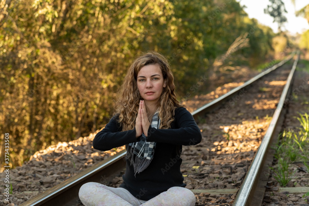Blonde Brazilian woman meditating on the rails of a train line Blonde Brazilian woman meditating on the rails of a train line