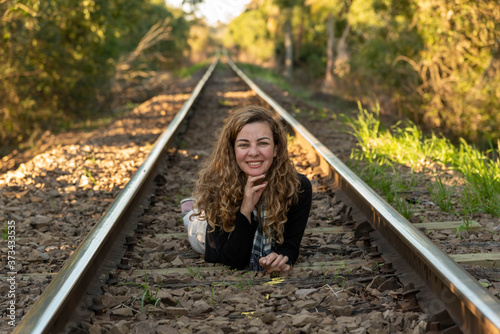 Blonde woman lying on the train line in the middle of nature
