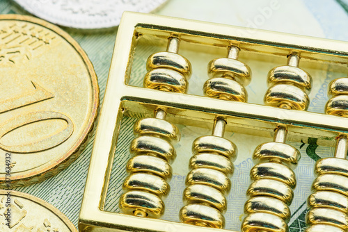 Golden abacus and coins on a banknote. Chinese abacus on pile of money, depicts world economy and global currency tradind for capital gain, investors or trader speculates or invest for profit margin. photo