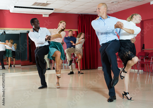 Portrait of young positive people practicing vigorous jive movements in dance class