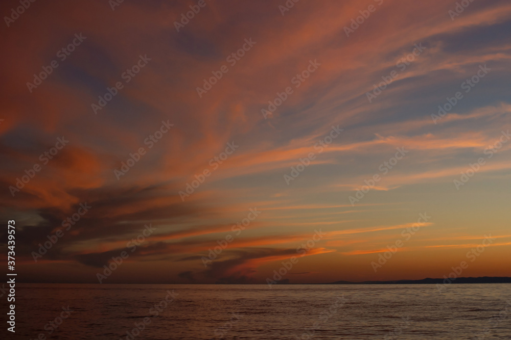 Dramatic red yellow clouds after sunset in the dusk on Lake Baikal, beautiful scenic seascape, dark moody style