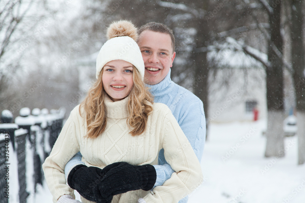 Young couple in knitted sweaters hugging in a winter park Young couple in knitted sweaters hugging in a winter park