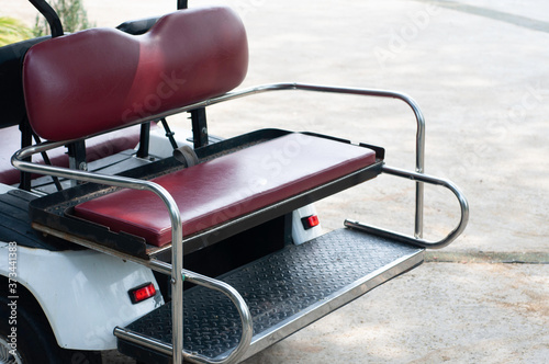 Back of golf cart with dark red leather seat, electric power vehicle.