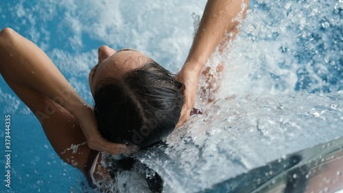 Close-up young woman getting hydrotherapy in the pool of a spa hotel. Beautiful girl relaxing with hydromassage