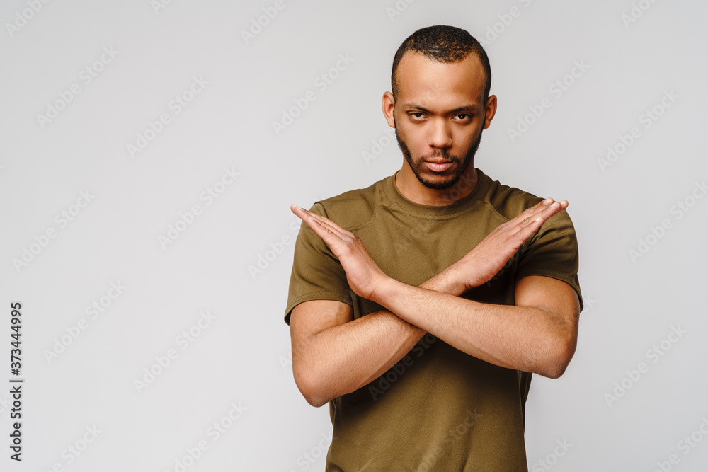 african american young man gesturing STOP with his hands crossed over light grey background african american young man gesturing STOP with his hands crossed over light grey background