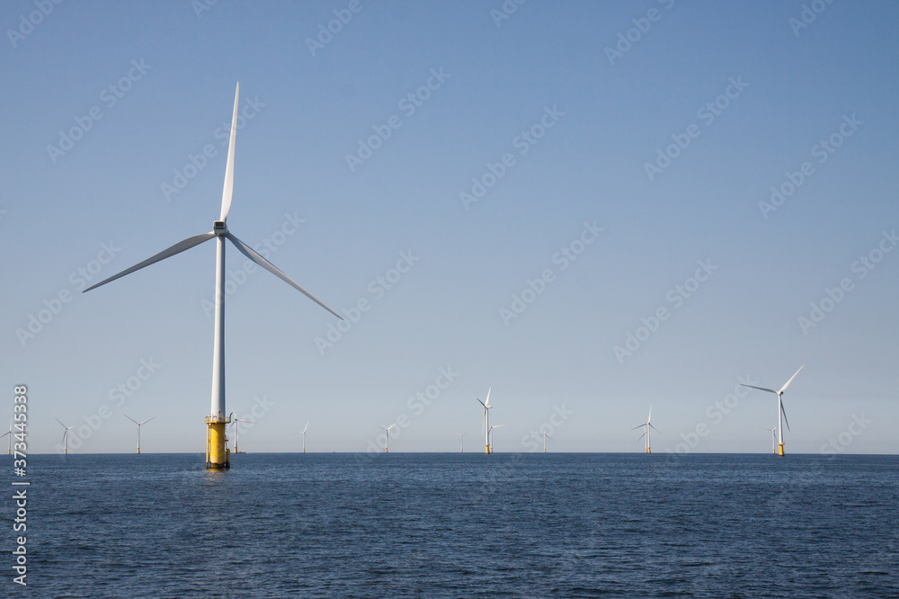 Wind turbines in an offshore wind farm in the North Sea just off the coast of the Netherlands, on a clear day. Wind turbines in an offshore wind farm in the North Sea just off the coast of the Netherlands, on a clear day.