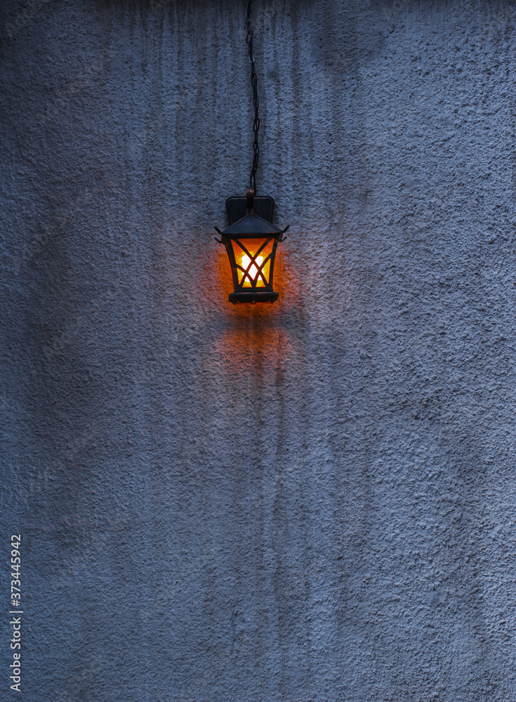 Bright lantern on a gray cement wall