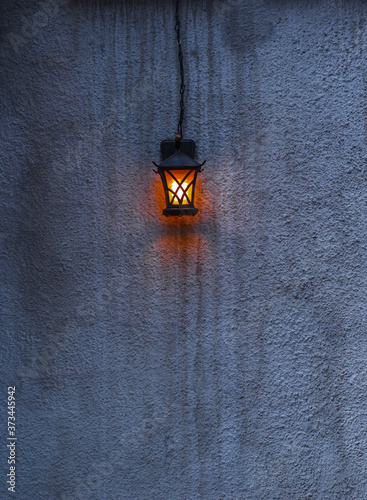 Bright lantern on a gray cement wall