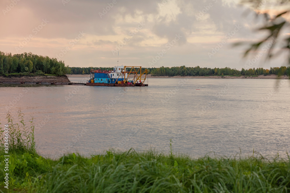 A landscape with river dredger using the method of hydro-mechanization against a sunset sky. Hydraulic sand washing and mining. Copy space