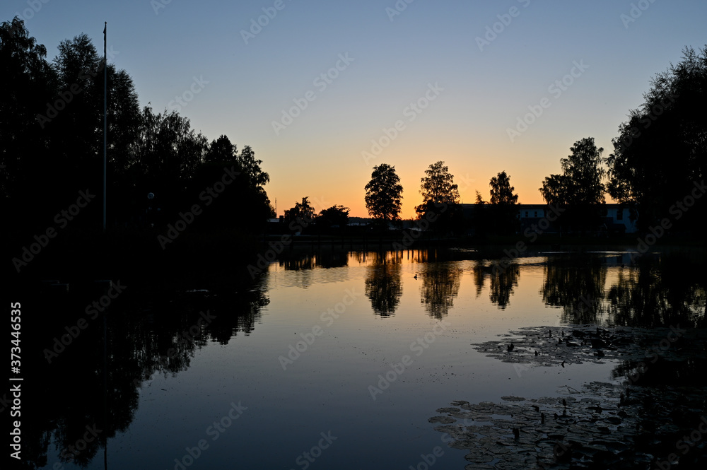 Obraz premium sunset over calm pond in silent park