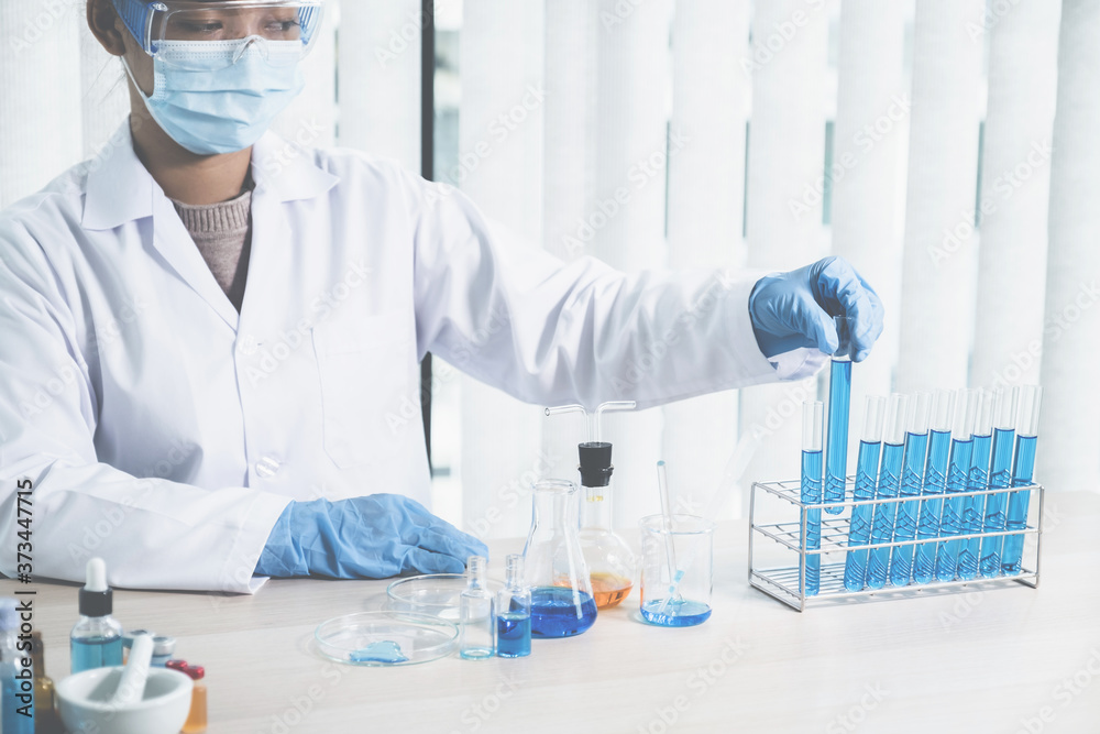 Scientists hold a glass tube filled with blue chemical liquid for research and analysis in a laboratory Scientists hold a glass tube filled with blue chemical liquid for research and analysis in a laboratory