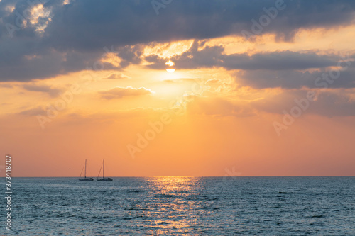 Seascape at sunset of the day. Calm. Sunset at sea. Sky with dark clouds in the sun Sailboats in the sea at sunset © Оксана Корниенко