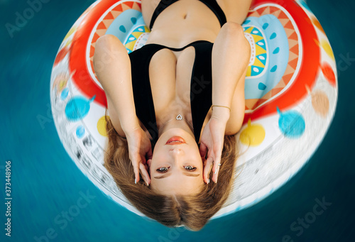 Amazing blonde with a beautiful figure lying in the pool on an air mattress. Vacation concept. © Yuliia