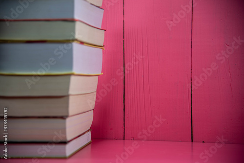 Stack of paper books on pink background