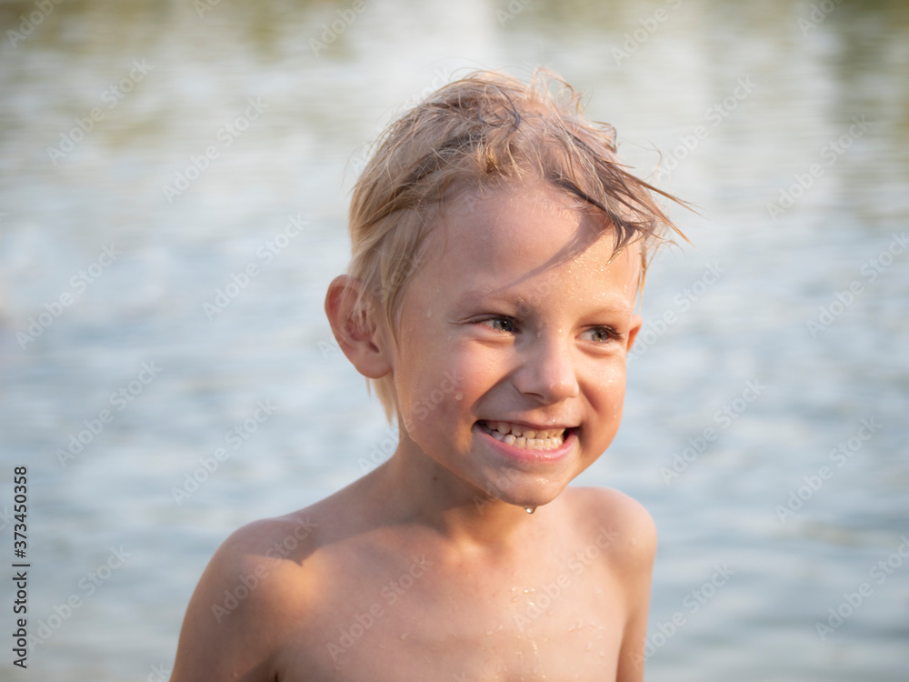Portrait of a funny caucasian preschool boy with wet hair is resting on the lake Portrait of a funny caucasian preschool boy with wet hair is resting on the lake