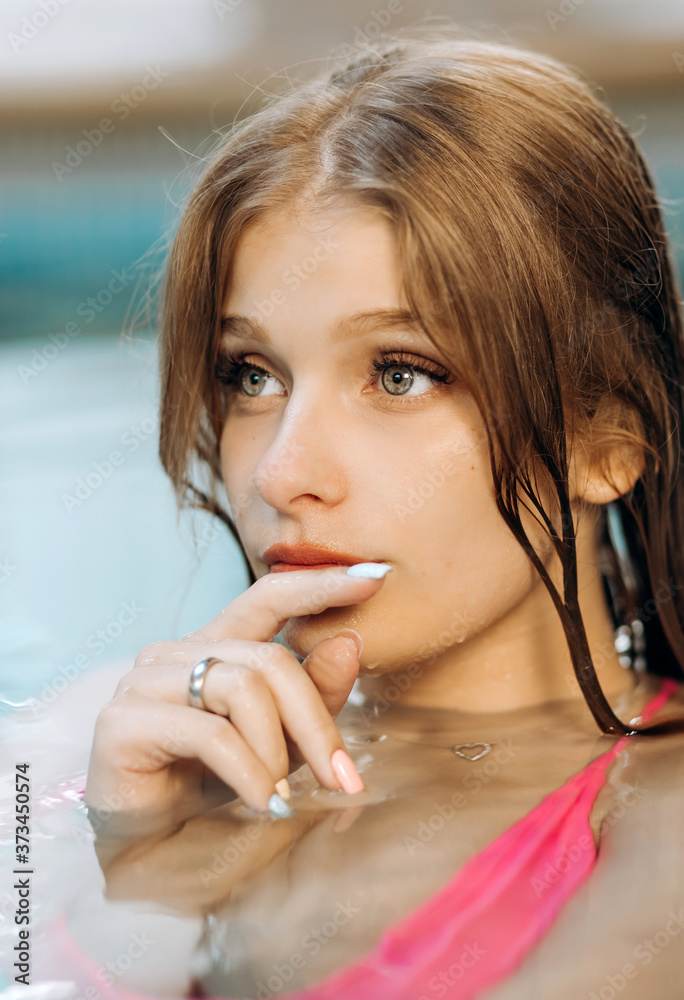 Portrait of a sexy blonde in the water. Young girl in a pink swimsuit swims in the pool. Portrait of a sexy blonde in the water. Young girl in a pink swimsuit swims in the pool.