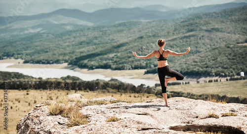 Yoga time. Stretching and Outdoors training. Female wearing sportswear. Balance position. Breathtaking view. Copy space