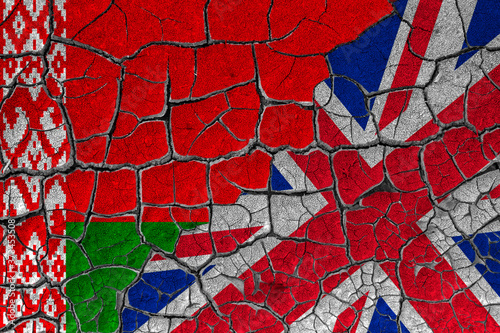 Flags of Belarus and Great Britain on a cracked wall, dry land. Concept of relationship or conflict between countries 