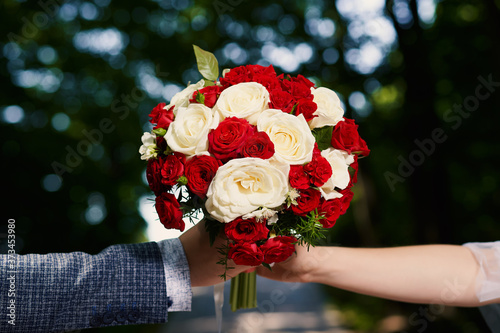 Close-up of the bride and groom holding a beautiful wedding bouquet in red colors