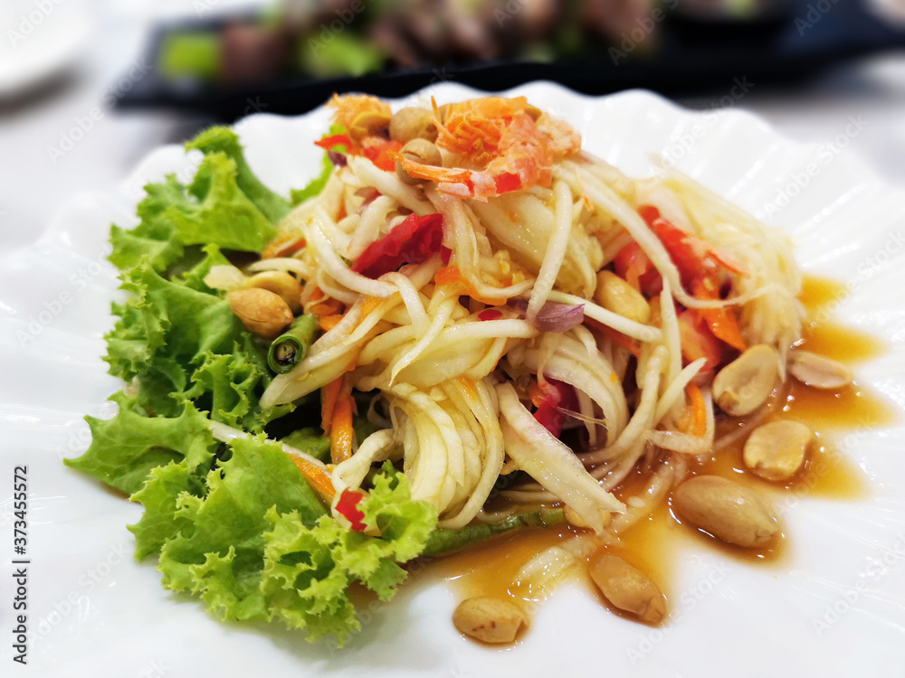Thai papaya salad with dried shrimp, peanuts, chillies, tomatoes and yard long bean.  Spicy Thai salad.  Selective focus.
