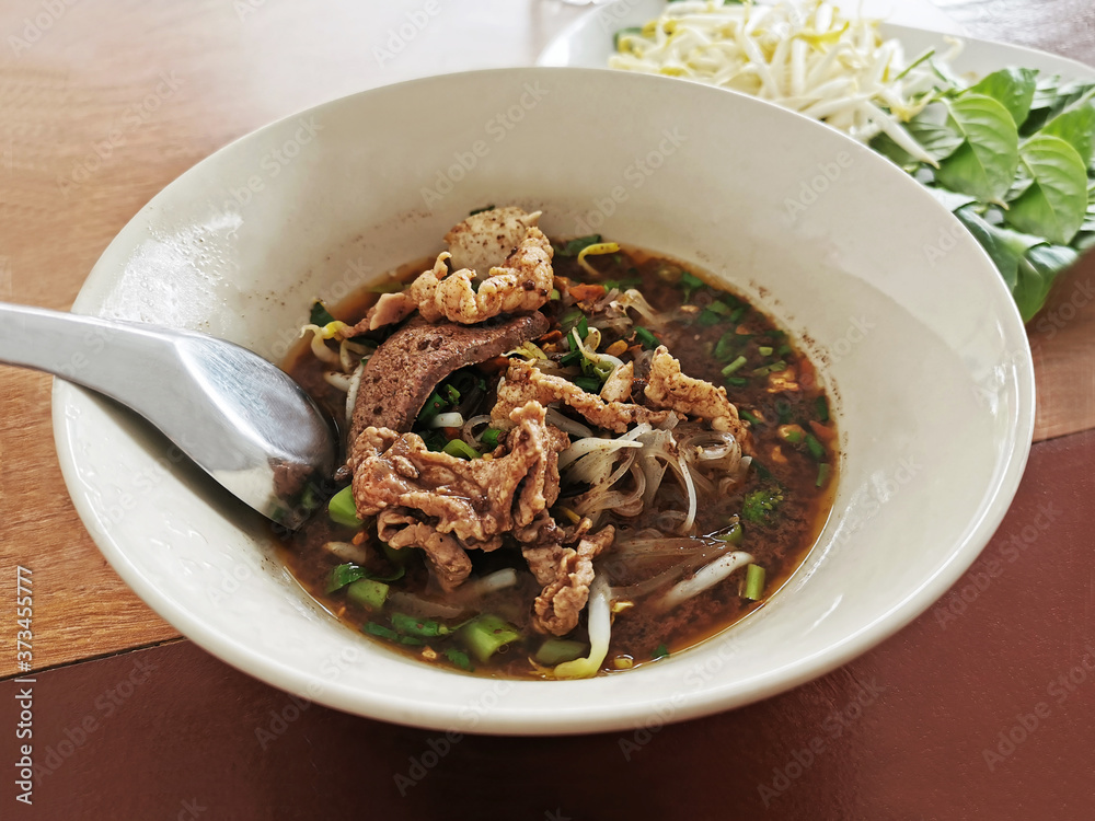 Fine cut white rice noodle thicken soup with sliced pork, sliced pork liver, fine cut morning glory, sprouts and culantro or Vietnamese coriander.  Thai boat noodle soup.  Selective focus.