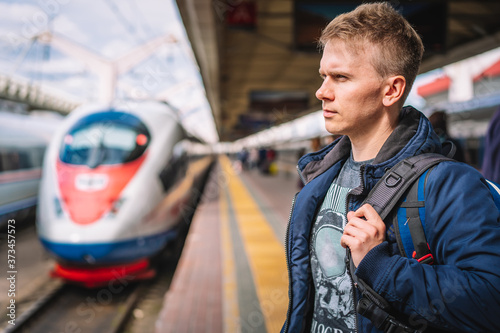 Moscow / Russia - 15 Aug 2020: A young man with a backpack is standing on the platform at the railway station waiting to Board the train