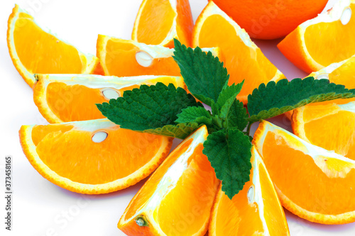 Macro view of orange with sections and green leaf of mint on white background