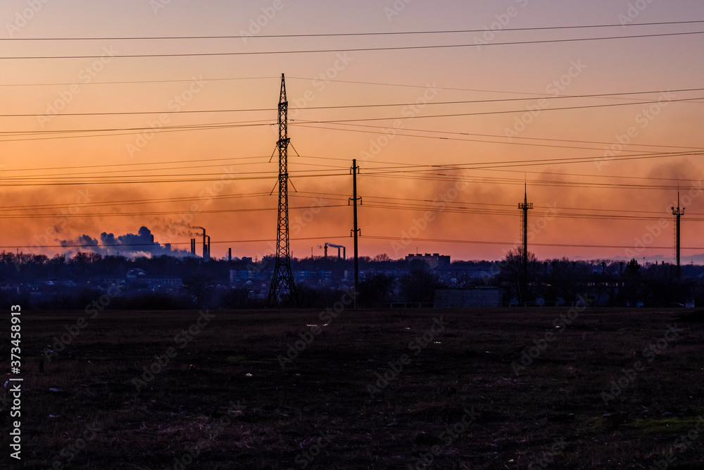 View on smoke pipes of the factory at sunset