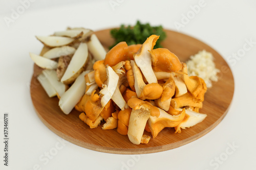 Ingredients for delicious fried potatoes with chanterelles and onions in a black plate with a fork on a wooden stand in the form of a rabbit